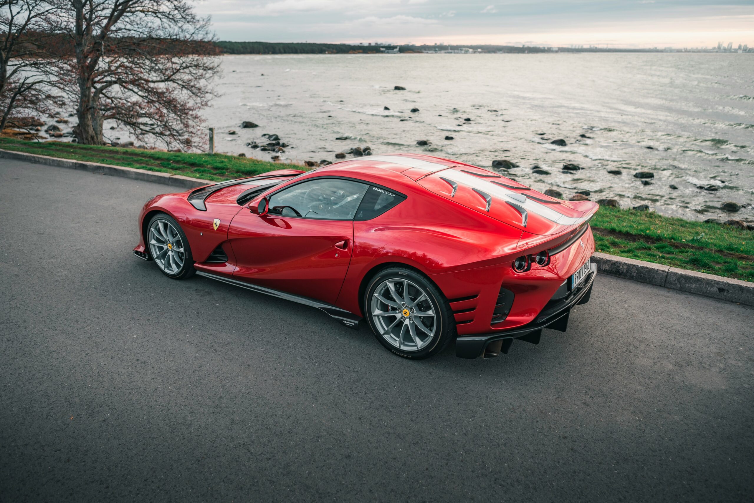 a red sports car driving down a road next to a body of water